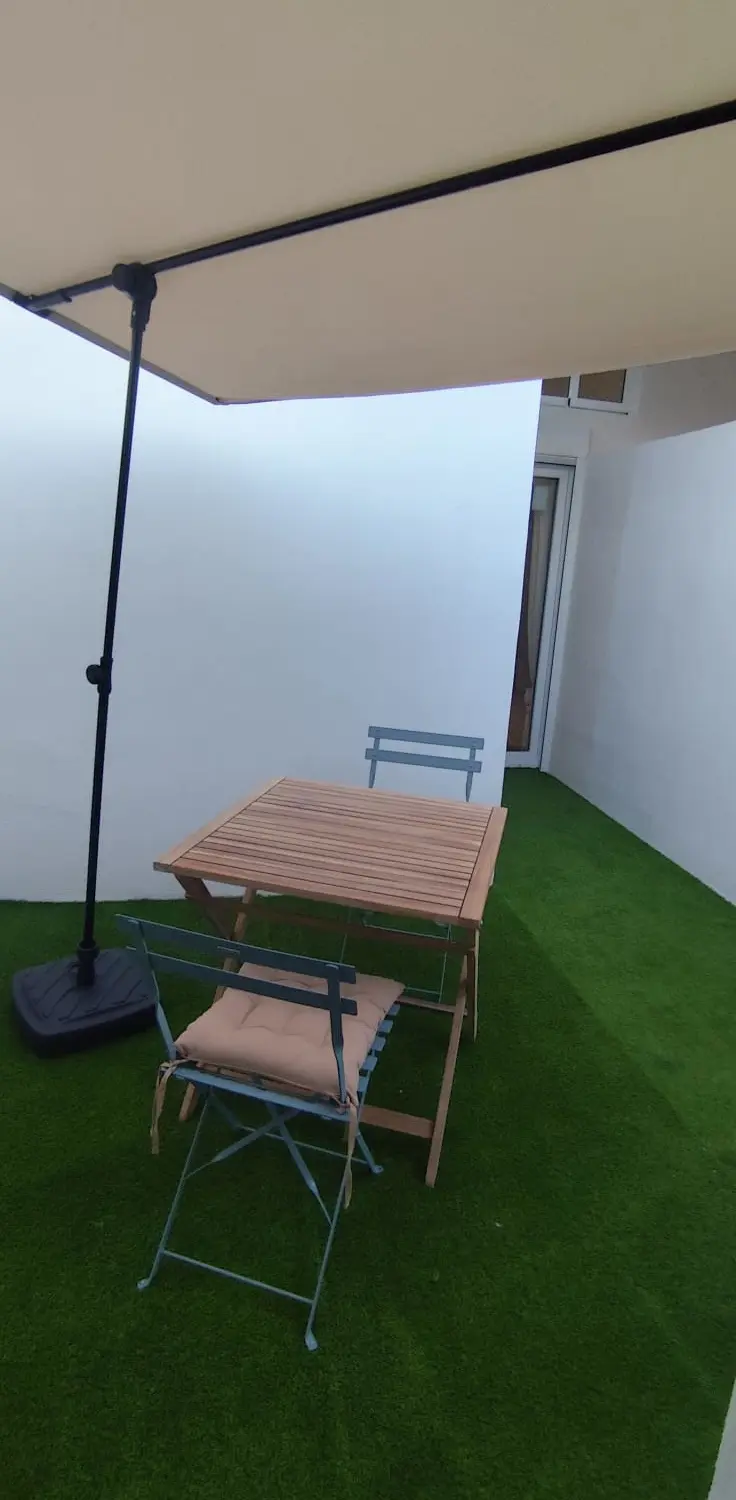 Patio privado con césped artificial y mesa de exterior